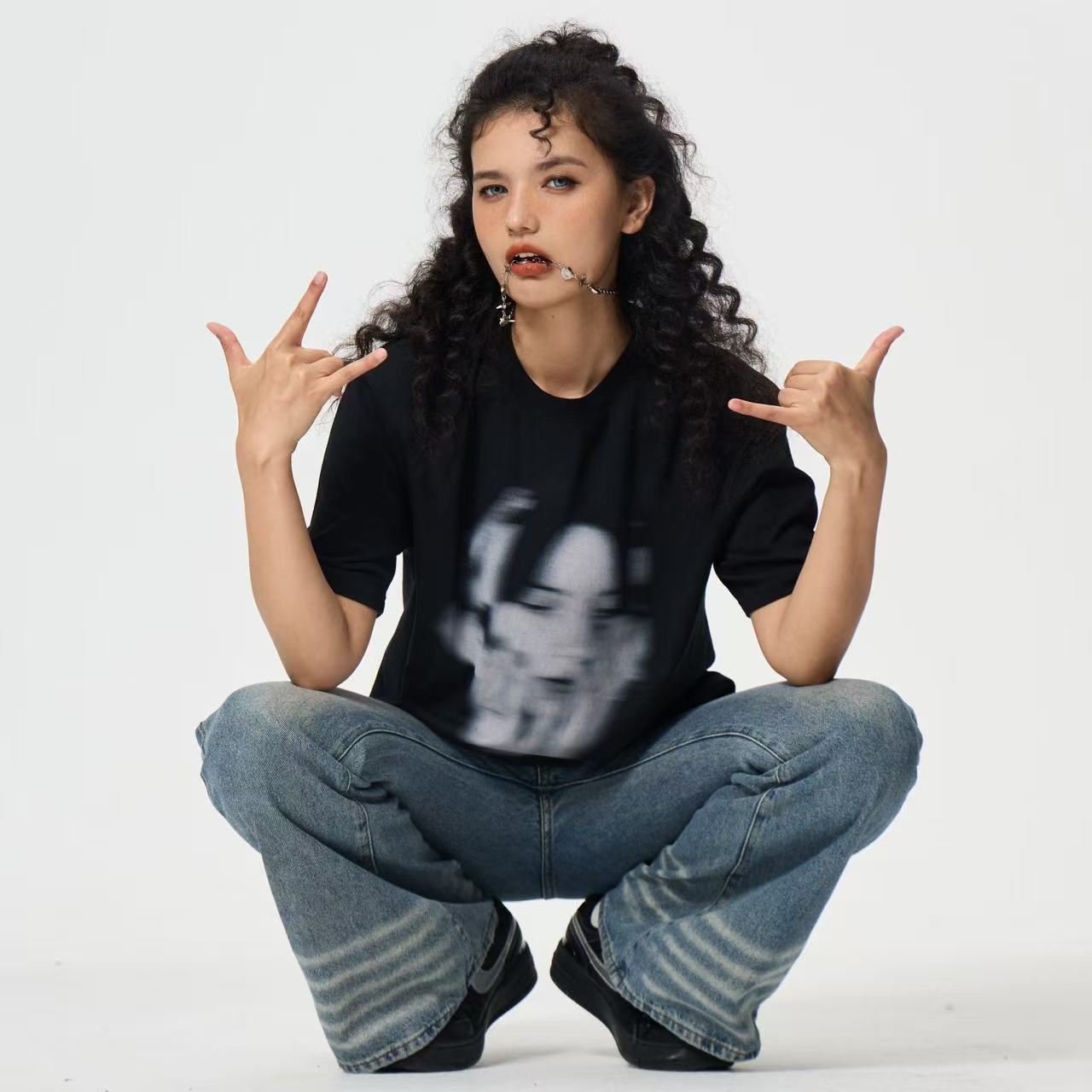 GLOWNVOA Model Image Artworks series image Person wearing a black t-shirt with a graphic design, sitting cross-legged on a white background